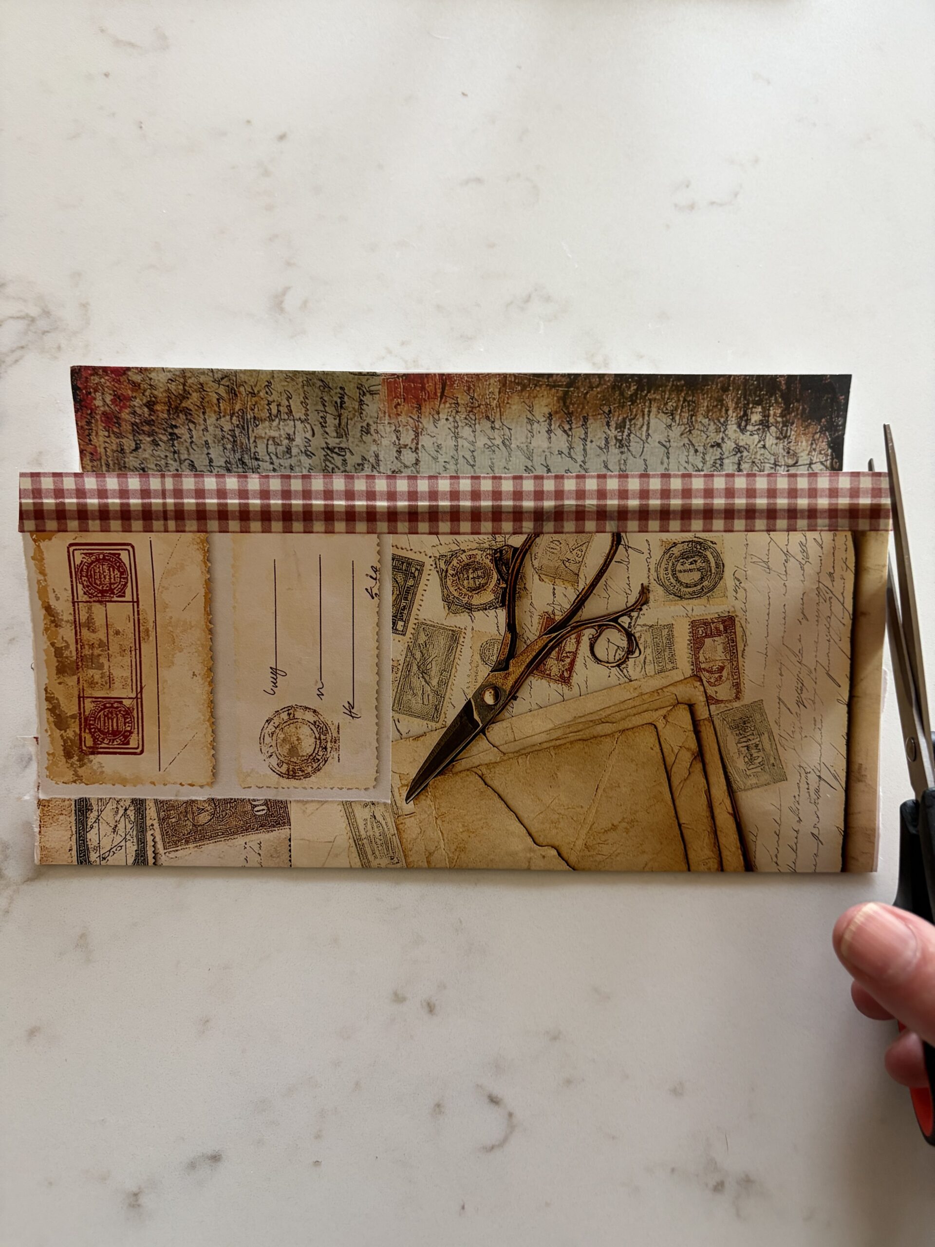 Adding washi tape to the edge of an old envelope covered with junk journal ephemera