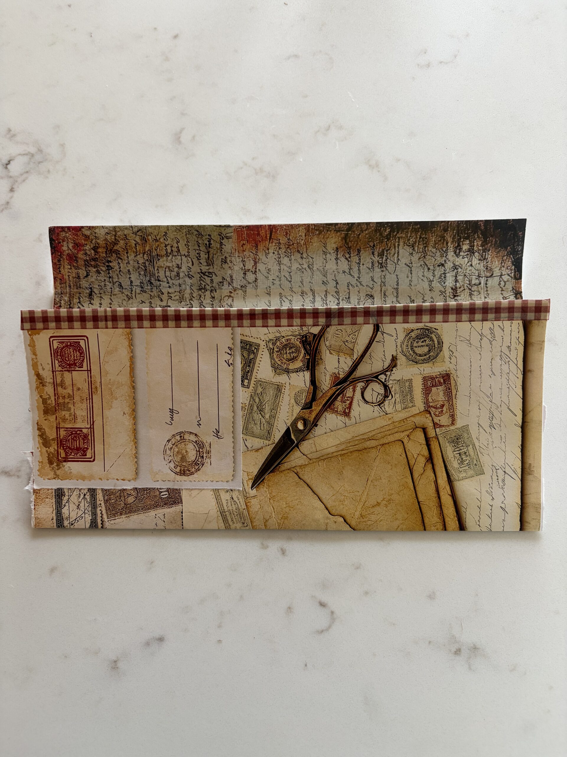 Washi tape added to the edge of an old envelope covered with junk journal ephemera