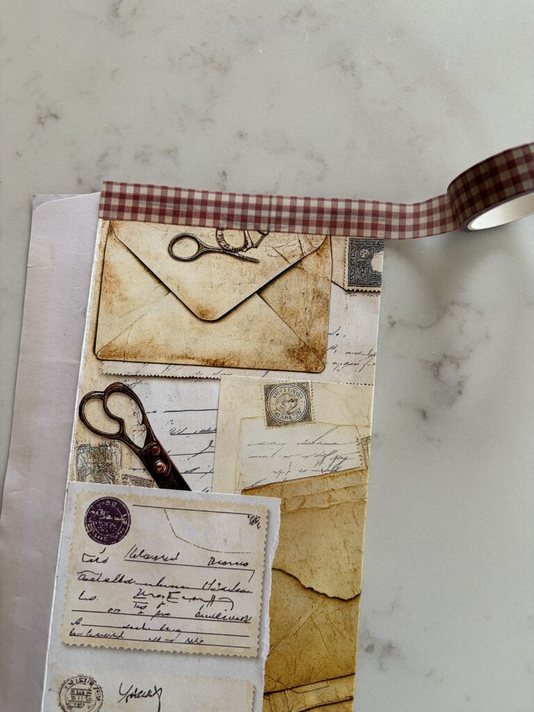 Adding washi tape to the side of an old envelope covered with junk journal ephemera